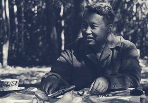 Saloth Sar, mais conhecido como Pol Pot, nasceu em 1925 em uma família de fazendeiros no Camboja (na época Indochina francesa). O jovem estudou nas melhores escolas e, com 20 anos, viajou a Paris para estudar rádio graças a uma bolsa. Na França, Pol Pot conheceu as ideias marxistas e aproximou-se do Partido Comunista Francês. Retornou ao Camboja em 1953, com 28 anos, unindo-se imediatamente ao movimento comunista e à luta pela independência, conquistada no ano seguinte. Em 1962, Pol Pot assumiu o controle do Partido Comunista do Camboja tornando-se Secretário-Geral (cargo que ocupou até 1981). Fugindo às perseguições do governo de Sihanouk, refugiou-se na floresta, onde começou a organizar e armar um grupo de resistência baseado nas táticas de guerrilha, o Angkor/Khmer Vermelho. Na estrutura do grupo, ele era o “Irmão número 1”. Na foto, da década de 1980, Pol Pot no seu santuário de Phnom Malai, na faixa de fronteira com a Tailândia.