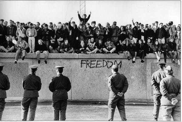 Estudantes da Alemanha Oriental no Muro de Berlim, diante de guardas de fronteira, em 9 de novembro de 1989